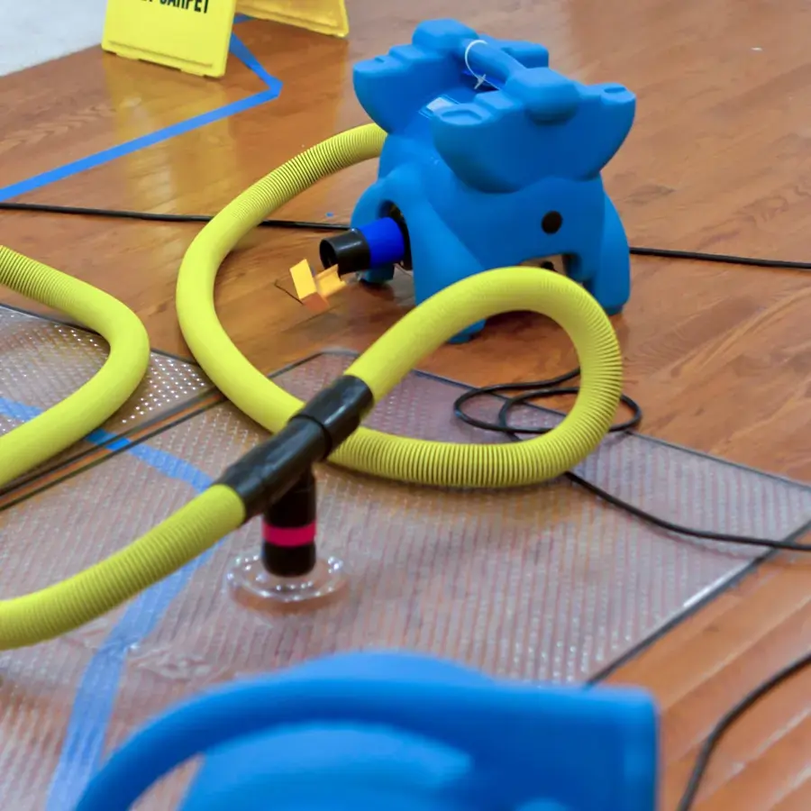 Drying mat and hose pulling moisture out of a wet hardwood floor in Huntersville