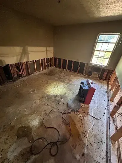 Flood-cut room with drywall removed and a dehumidifier drying the slab