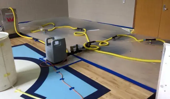 Floor drying system with hoses taped across a wet gym floor
