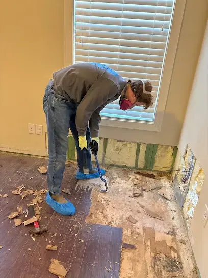 Removing water-damaged flooring along a flood-cut wall in a Huntersville home